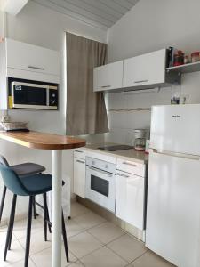 a kitchen with white appliances and a wooden table at Lantana in Sainte-Anne