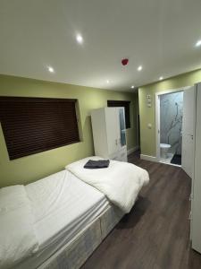 a bedroom with a white bed and a bathroom at Cozy en-suite 15 minutes from Heathrow Airport by car in South Ruislip Station