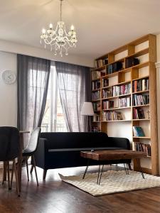 een woonkamer met een zwarte bank en een kroonluchter bij Apartament Villa Park in Ełk