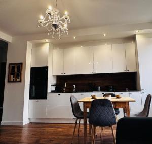 een keuken met een tafel en stoelen en een kroonluchter bij Apartament Villa Park in Ełk +15 foto's