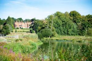 a lake with a house in the background and a building at Outlook farm cabin firepit in Hertford