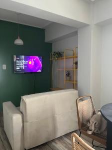 Depto San Lorenzo y Alberdi في سان ميغيل دي توكومان: غرفة معيشة مع أريكة وتلفزيون على جدار أخضر