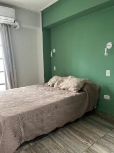 Depto San Lorenzo y Alberdi في سان ميغيل دي توكومان: سرير في غرفة نوم مع جدار أخضر