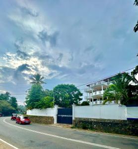 Ein rotes Auto fährt eine Straße entlang neben einem Gebäude in der Unterkunft French Residence Tangalle in Tangalle + 12 Fotos