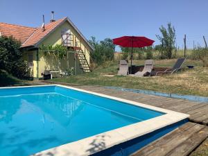 a swimming pool in front of a house with an umbrella at Ferienhaus Balaton in Szőlősgyörök