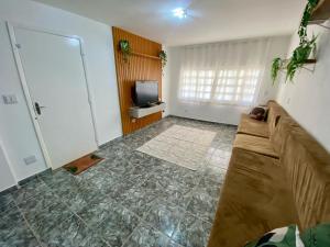a living room with a couch and a television at Casa Gonzalez Oliveira in Mongaguá