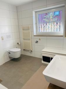 ein weißes Bad mit einem WC und einem Fenster in der Unterkunft Ferienwohnung Am Steinberg in Nauendorf + 10 Fotos