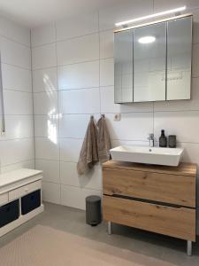 ein weißes Badezimmer mit Waschbecken und Spiegel in der Unterkunft Ferienwohnung Am Steinberg in Nauendorf