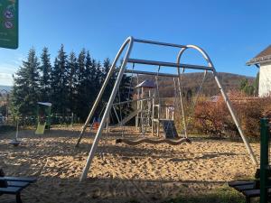a playground with a swing set in the sand at Ferienwohnung Am Steinberg in Nauendorf