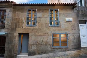 a stone house with three windows and a door at Casa Carmela Baiona in Baiona
