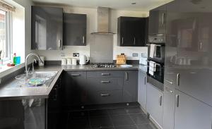a kitchen with stainless steel appliances and black cabinets at Margam's Gloucester House for Business Travellers in Cheltenham