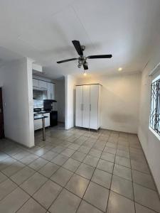 Habitación vacía con ventilador de techo y cocina. en Makers lodge Bnb, en Nelspruit