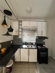 Una cocina con gabinetes blancos, un fregadero y una estufa. en Makers lodge Bnb, en Nelspruit