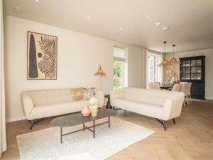 a living room with two white couches and a table at Pretty Holiday Home in De Koog Texel with Garden in Westermient
