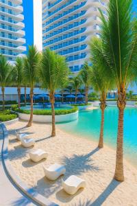 a swimming pool with chaise lounge chairs and palm trees at Tala Haven at Azure North Studio with Mt Arayat View in San Fernando