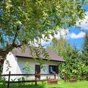 ein weißes Haus mit einem Zaun und einem Baum in der Unterkunft Sielsko Anielsko Uniejów- domki całoroczne in Uniejów