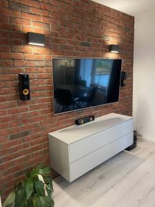 une télévision sur un mur de briques avec un meuble blanc dans l'établissement Zentrale Wohnung 1OG mit WLAN & Kaffee, à Paderborn