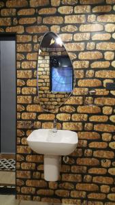 La salle de bains est pourvue d'un lavabo et d'un miroir sur un mur en briques. dans l'établissement Goan Cozy 2 Bedroom Abode, à Calangute