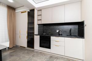 a kitchen with white cabinets and black appliances at Brand New Flat Near Cafes and Shops I Full Ameneties in Floreşti +15 photos