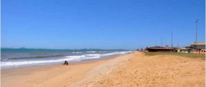 a person walking on a beach with the ocean at Casa simples e aconchegante em Unamar - Cabo Frio in Tamoios
