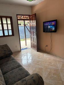 a living room with a couch and a flat screen tv at Casa simples e aconchegante em Unamar - Cabo Frio in Tamoios