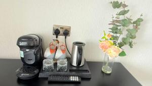 a coffee maker on a table next to a vase with flowers at Armadillo Guest House- Adults Only in Edinburgh