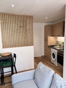 ein Wohnzimmer mit Couch und Tisch und eine Küche in der Unterkunft Le Cocon Vert in Cognac