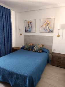 Un dormitorio con una cama azul con pinturas en la pared en Palmeras del Sur Juan, en Playa de las Américas