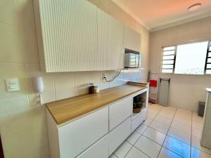 una cucina con mobili bianchi e un piano di lavoro in legno di Apê charmoso a 2km do Centro - 4km do Pq Aquático ad Águas de Lindóia