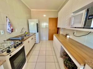una cucina con mobili bianchi, un lavello e un frigorifero di Apê charmoso a 2km do Centro - 4km do Pq Aquático ad Águas de Lindóia Altre 27 foto