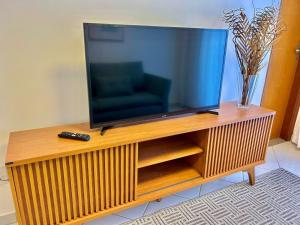 una TV a schermo piatto su un centro di intrattenimento in legno di Apê charmoso a 2km do Centro - 4km do Pq Aquático ad Águas de Lindóia