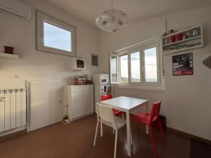 的里雅斯特UrbanNest Trieste的厨房配有白色的桌子和红色的椅子