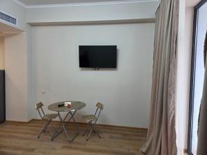 Habitación con mesa, sillas y TV en la pared. en Alvina White Tsaghkadzor, en Tsaghkadzor