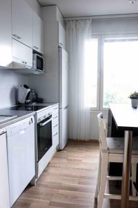 une cuisine avec des appareils blancs et une table avec des chaises dans l'établissement Compact apartment, à Rovaniemi