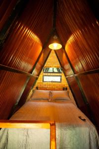 a bed in a wooden room with a window at Ybyra Pousada de Selva in Careiro