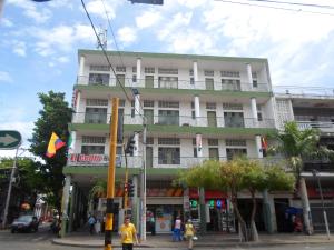 un edificio blanco alto con gente caminando delante de él en Gran Hotel El Cedro, en Girardot