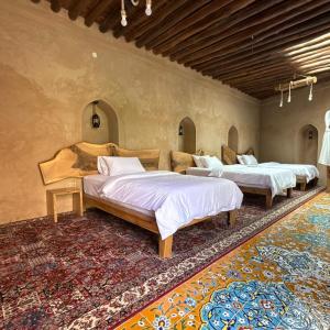 three beds in a room with a rug at Beit Al Fateh بيت الفتح in Fatḩ Āl Bū Sa‘īd