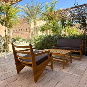 two wooden chairs and a bench on a patio at Beit Al Fateh بيت الفتح in Fatḩ Āl Bū Sa‘īd +24 photos