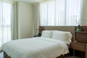 a bedroom with a bed with white sheets and windows at 1-BR Retreat w Park Sea Views in Panama City in Panama City