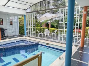 a pool with chairs and an umbrella in a house at Casa de recreo en conjunto residencial in Arbeláez