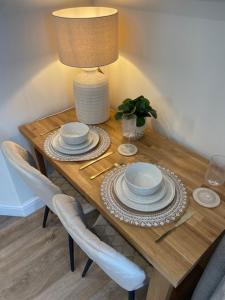 a wooden table with plates and a lamp on it at The Summer House - Tiny Home with Hot Tub in Coity