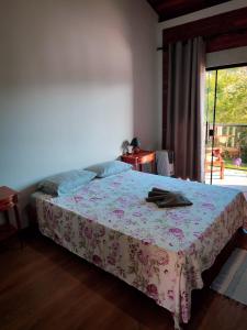 ein Schlafzimmer mit einem Bett mit einer Blumendecke und einem Fenster in der Unterkunft Pousada Finca dos Anjos in Passa Quatro + 24 Fotos
