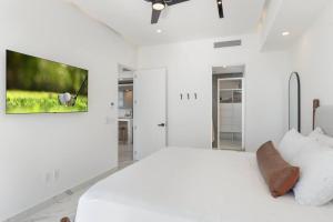 ein weißes Schlafzimmer mit einem großen Bett und einem Fernseher in der Unterkunft Encantame Soleil 1BR Sleeps 4 lock off unit in Playa Encanto + 36 Fotos