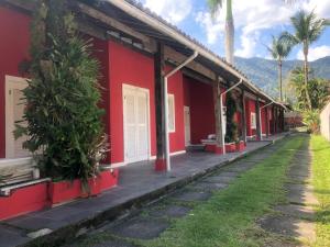 eine Reihe roter Häuser mit Palmen davor in der Unterkunft Vila Giulia in Maresias