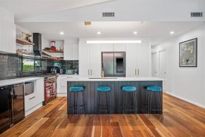 Eine Küche mit einer schwarzen Kochinsel und blauen Hockern in der Unterkunft 27 Burrawong Drive in Port Macquarie