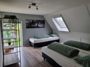 a attic room with two beds and a window at Vakantiewoning Stuifzand in Stuifzand