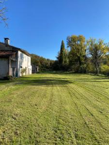 a large grass field next to a building and trees at Cà CASTIGLIONE in Acqualagna