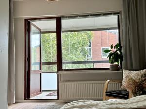 Cette chambre dispose d'une fenêtre avec une chaise et une plante. dans l'établissement Stylish marine studio, balcony, parking in Lauttasaari, à Helsinki