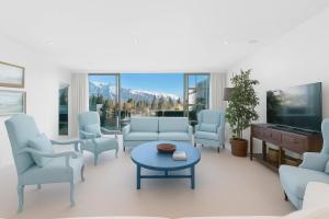 クイーンズタウンにあるTHE SHOTOVER Central Queenstown Luxuryのリビングルーム(青い椅子、テーブル、テレビ付)