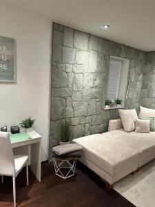 a bedroom with a stone wall with a bed and a desk at Ferienwohnung Casa Luma in Altendiez
